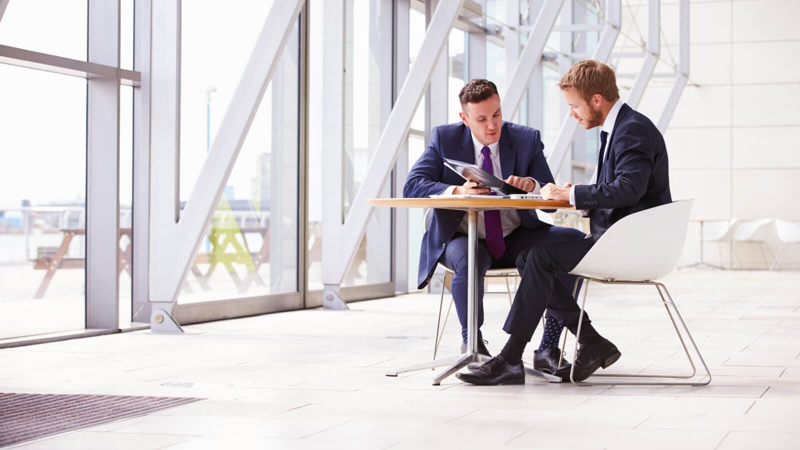 2 men in business suits working on a laptop