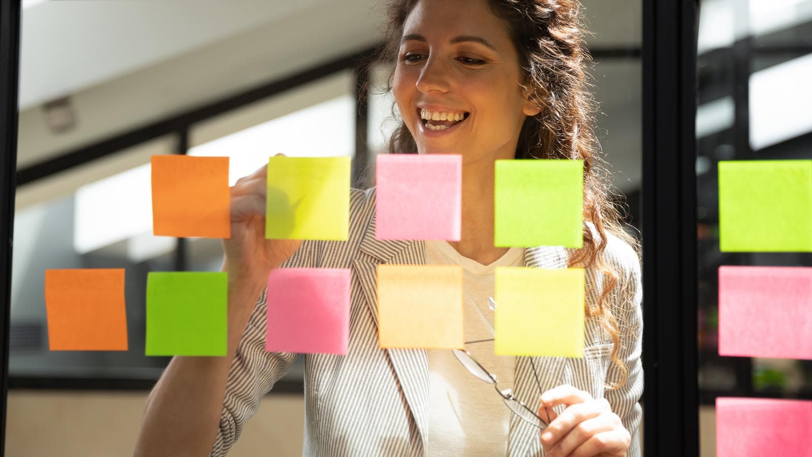 Woman merrily writing on colourful sticky notes on