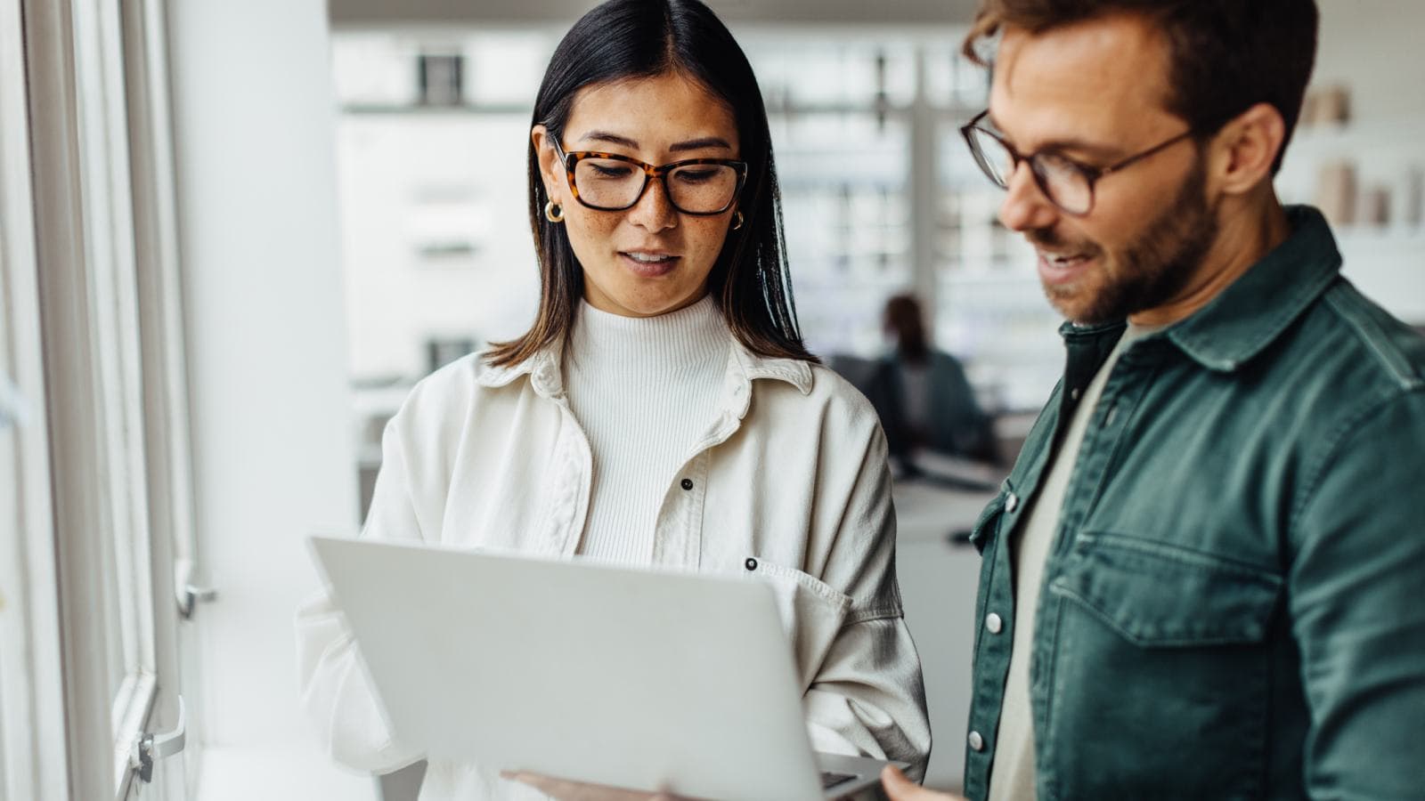 Man and woman standing, looking at laptop