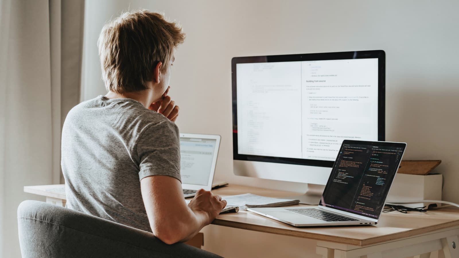 Person sitting at desk using 3 different screens