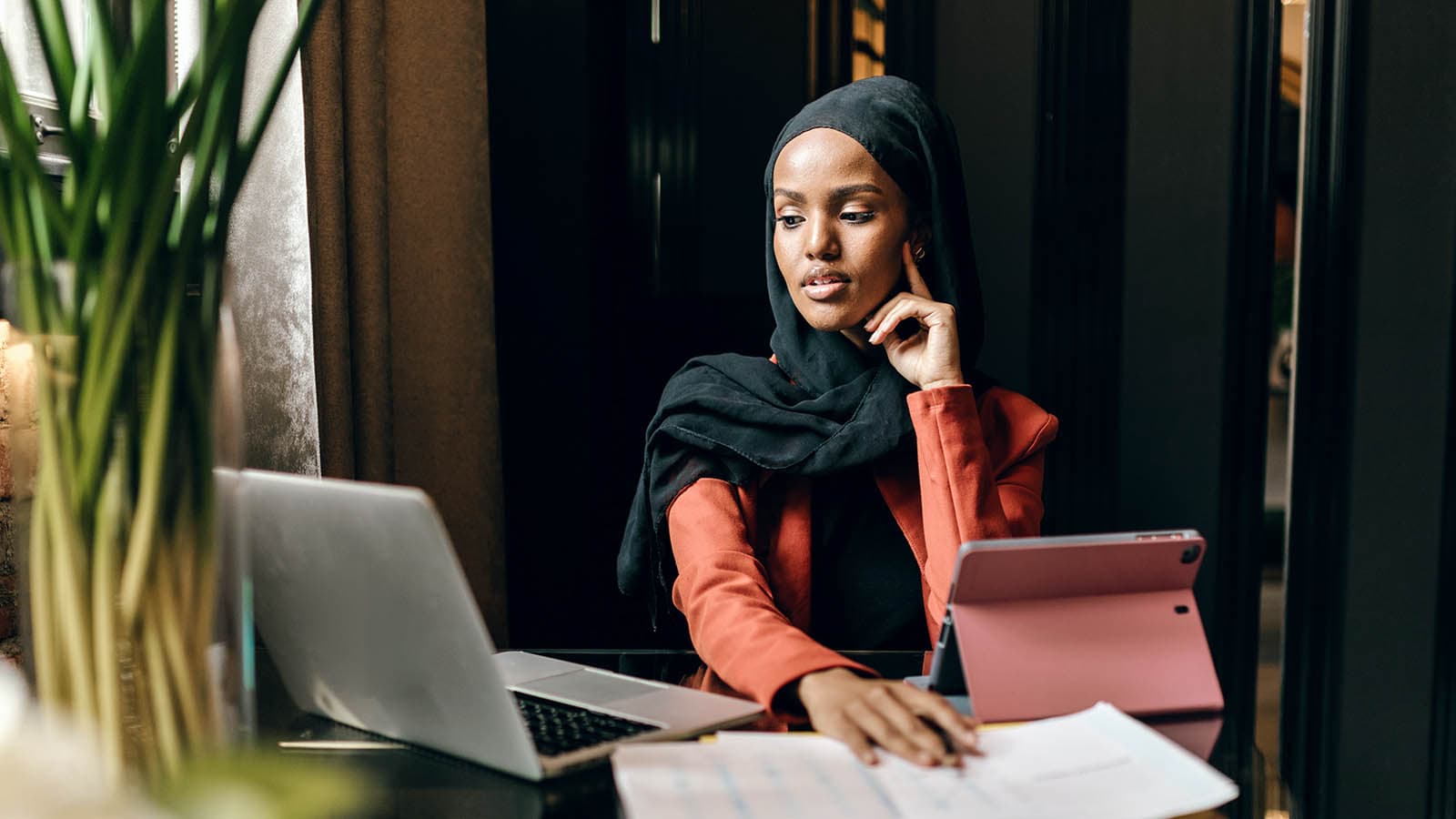 Woman looking at laptop next to iPad