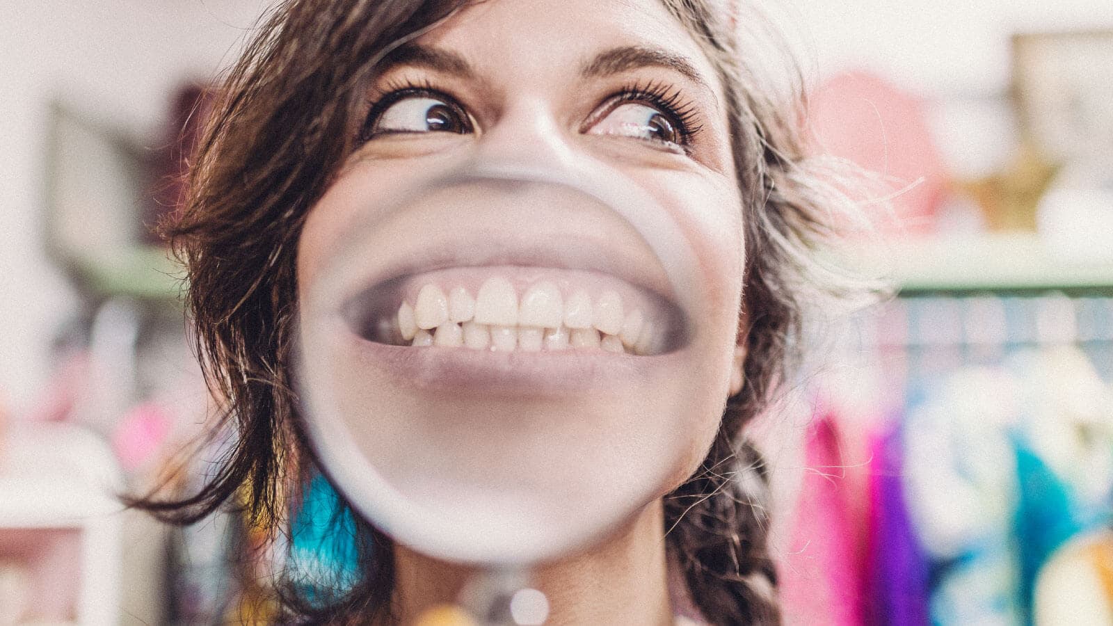Woman smiling through a bubble gum bubble