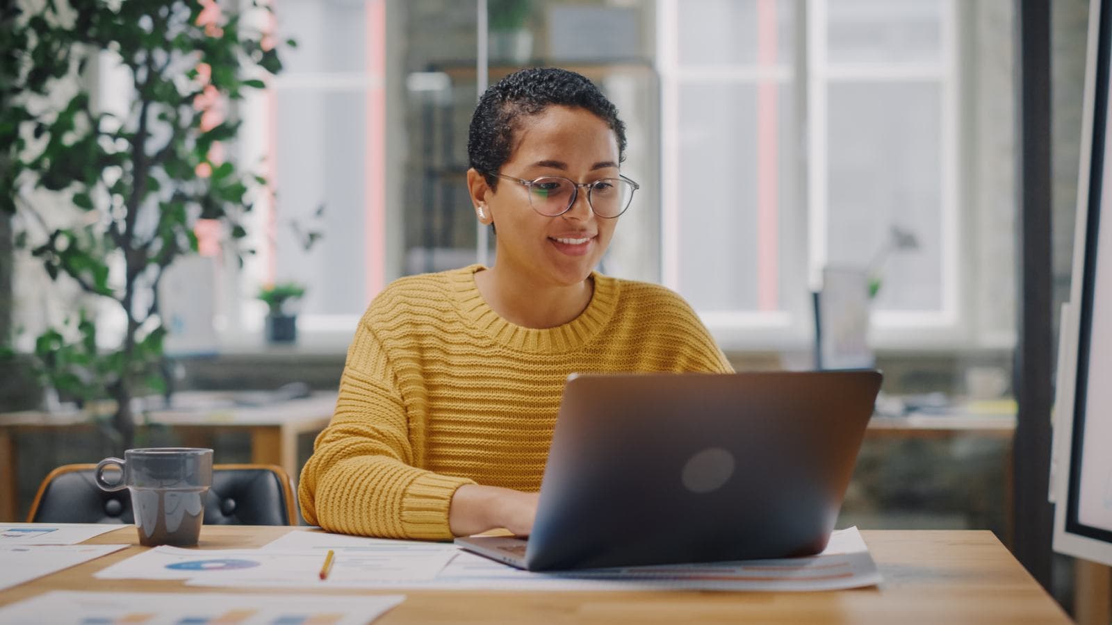 Woman with short hair and yellow jumper at desk