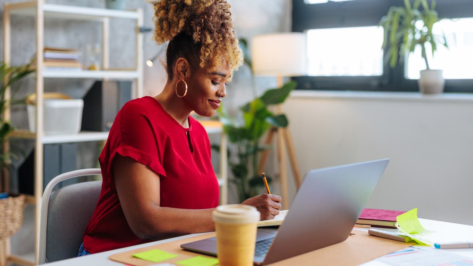 Woman with laptop, takeaway drink and sticky notes